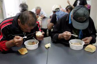Dos hombres de pocos recursos reciben comida gratis en una iniciativa de distribución municipal en Atenas (Grecia). EFE/Archivo