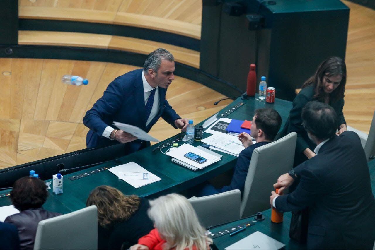 Momento en el que el portavoz de Vox, Javier Ortega Smith, se encara y tira una botella de agua vacía al edil Eduardo Fernández Rubiño, concejal de Más Madrid, en su escaño.