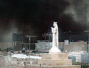 El humo de una explosión se alza tras una estatua de la Virgen en Belén.
