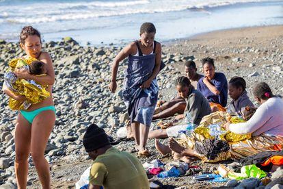 Una bañista sostiene en brazos a un bebé que llegó en patera a la playa del Águila (Gran Canaria).