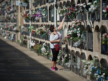 Una dona dipositant flors en un nínxol del cementiri del Poblenou.