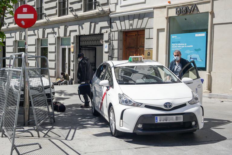 Un taxista con mascarilla deja a un pasajero en una calle de Madrid.
