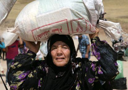 Una mujer siria llega a la frontera portando sus pertenencias en un saco sobre la cabeza.