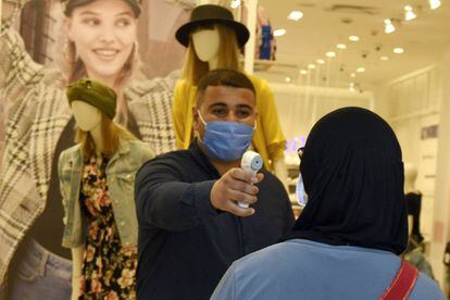 Un empleado toma la temperatura a una clienta antes de permitirle ingresar a una tienda de moda en Túnez. 