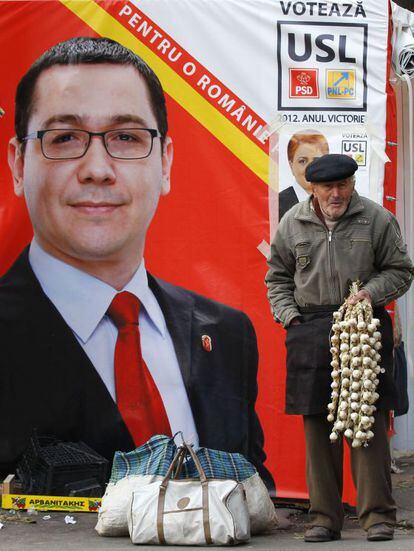 Un hombre vende ajos frente a un cartel del primer ministro Victor Ponta.