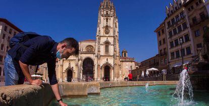 Un turista se refresca en la fuente de la catedral de Oviedo