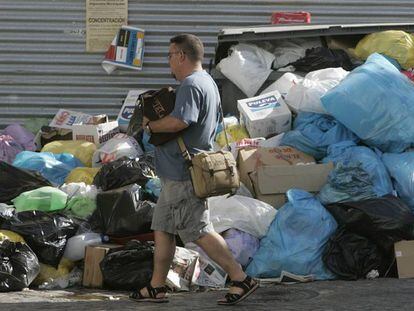 Un vecino de San Fernando pasa junto a la basura acumulada junto a un contenedor.