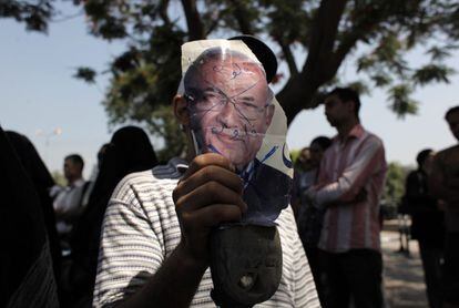Un manifestante egipcio sostiene un zapato y una fotografía con el rostro tachado de Shafiq.