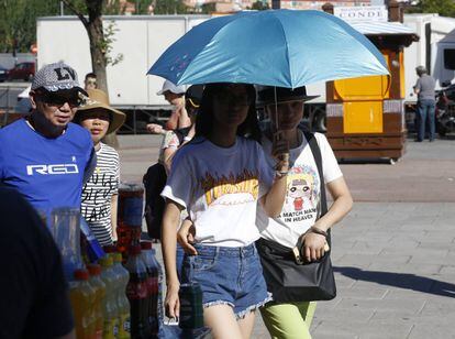 Dos turistas se protegen del sol con un paraguas, en el exterior de la Plaza de las Ventas en Madrid.