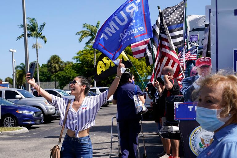 Una joven se toma una foto delante de un centro de votación donde hay seguidores de Trump en Hiealeah, Florida.