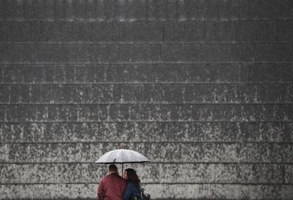 Una pareja se protege con un paraguas de la lluvia que desde primeras horas de la mañana cae sobre Pamplona. 