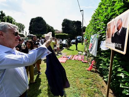 Un hombre hace una foto del retrato de Silvio Berlusconi, junto a la casa del ex primer ministro italiano.