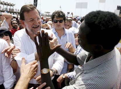 El líder del PP, Mariano Rajoy, saluda a un inmigrante, en un mitin celebrado el pasado mes de  mayo en Alicante.