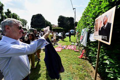 Un hombre hace una foto del retrato de Silvio Berlusconi, junto a la casa del ex primer ministro italiano.