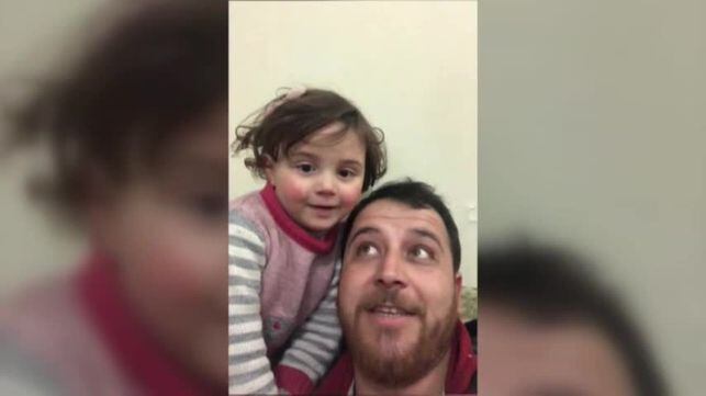 El sirio Abdalla, junto a su hija Salwa, mientras juega con ella para que las bombas no le afecten.