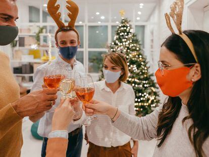 Un grupo de personas con mascarilla durante un brindis por Navidad. GETTY IMAGES