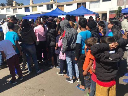Menores y adultos reciben alimentos mientras esperan ser atendidos por el Consulado chileno en Tacna (Perú).