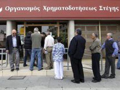 Varias personas esperan ante una sucursal de la Corporaci&oacute;n Financiera de la Vivienda de Chipre.