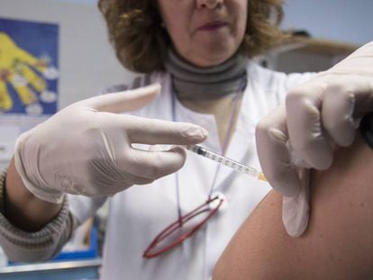 Una infermera injecta una vacuna al braç d'un pacient.