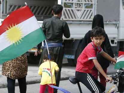 Un niño kurdo monta en una bici decorada con banderas kurdas frente a un centro electoral en Erbil, en la región autónoma del Kurdistán iraquí.