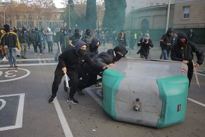 Manifestantes independentistas arrastra un contenedor durante el enfrentamiento con los 'mossos' en Barcelona.