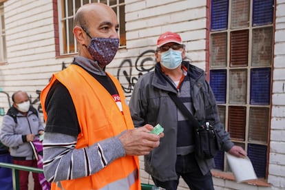 MADRID. 17-10-2020. Jesús (con chaleco naranja), de 54 años y empleado desde hace 34 en el room service del Hotel Palace, es voluntario en los repartos de comida a familias necesitadas en Aluche. Cada sábado se distribuyen varias toneladas de alimentos a personas golpeadas por la pandemia desde una red vecinal paralela a los canales oficiales de ayuda del Ayuntamiento. FOTO: LUIS DE VEGA