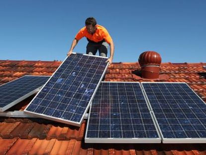 Un técnico instala placas solares en el tejado de una vivienda.