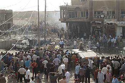 Decenas de curiosos observan los restos de una comisaría de policía atacada ayer con un coche bomba en Bagdad.