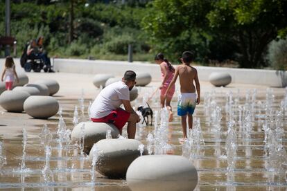 Varias personas se refrescan con unos surtidores en un parque en el barrio de Sant Andreu de Barcelona, este sábado.