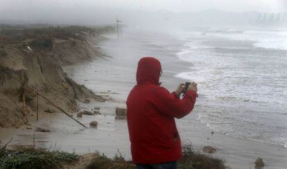 Un hombre toma imágenes de la playa de El Saler, comida por el temporal que ha obligado a la Autoridad Portuaria de Valencia a cerrar de nuevo el puerto de Valencia debido a las adversas condiciones meteorológicas.