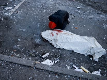 Un hombre junto al cadáver de un familiar muerto en el bombardeo a un edificio residencial en Kiev, este jueves.