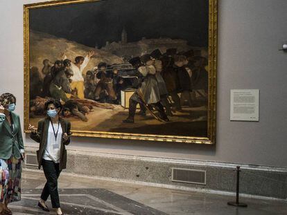 Dos visitantes del Prado pasan delante de 'Los fusilamientos' de Goya.