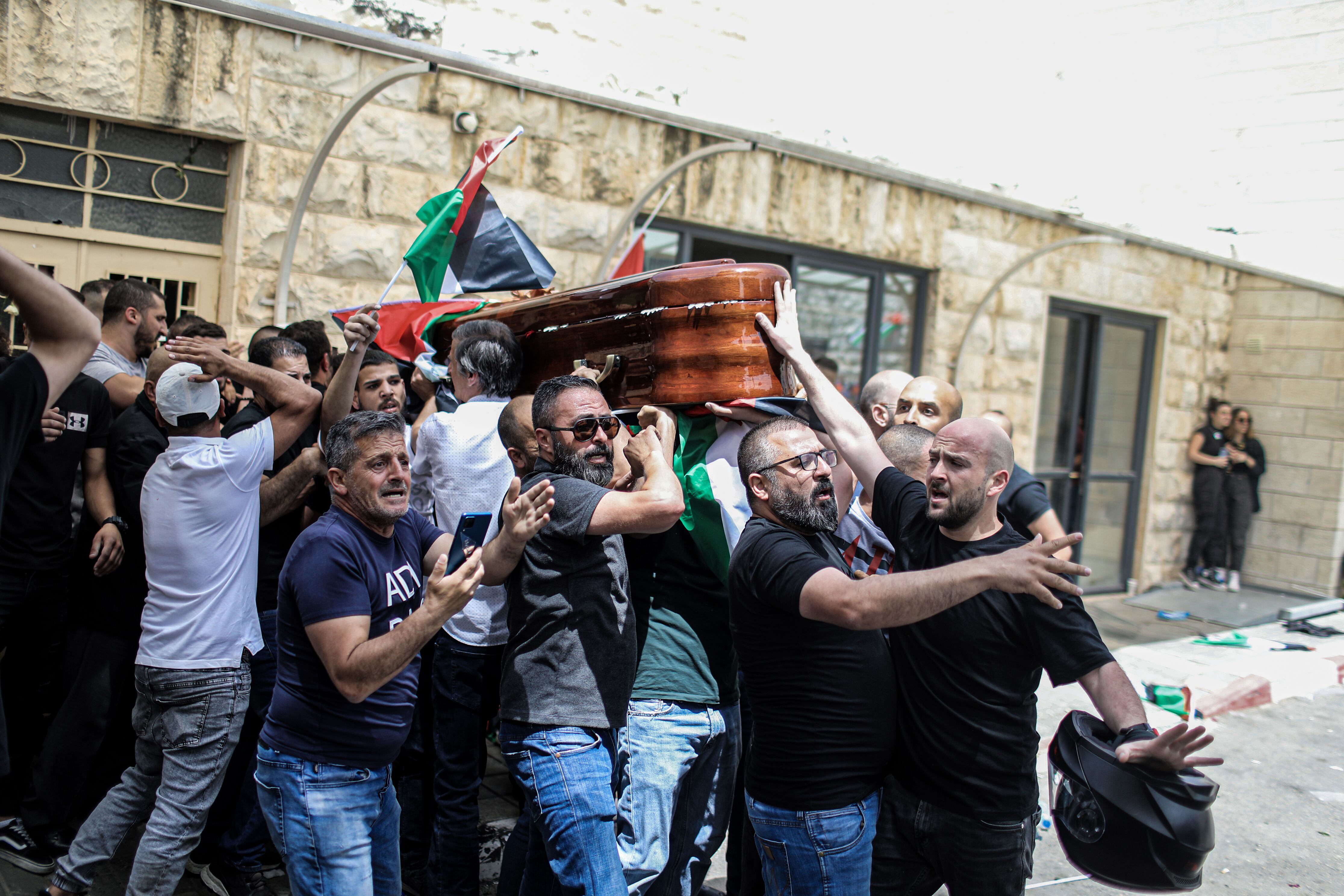 Los porteadores del ataúd de la periodista palestina-estadounidense Shikreen Abu Akleh, a la salida del hospital, antes de iniciarse el cortejo fúnebre.