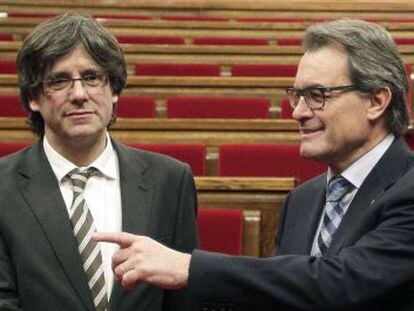 El expresidente Artur Mas (d) y el nuevo presidente de la Generalitat, Carles Puigdemont (d), se saludan a la finalizaci&oacute;n del pleno celebrado esta tarde en el Parlament de catalu&ntilde;a.