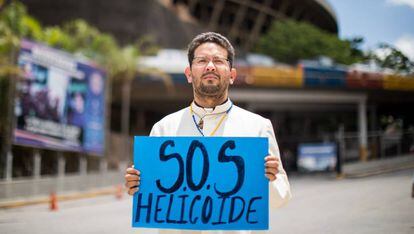 Un sacerdote sostiene un cartel frente a la sede del Servicio de Inteligencia, en Caracas.