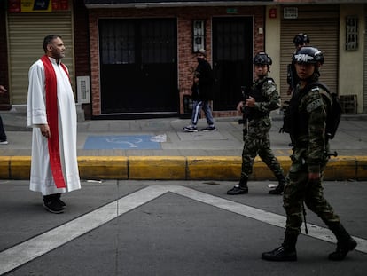 Un sacerdote católico junto a soldados del Ejército de Colombia, en una calle de Bogotá, en abril de 2023.
