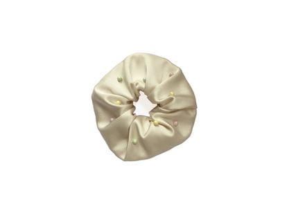 Betolaza.
La firma española confecciona a mano sus accesorios de pelo. El scrunchie es de seda satinada y está adornado con pequeñas perlas de color pastel. 35 euros.