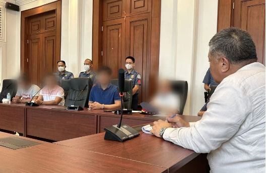 Los tres agentes imputados comparecen en Manila ante el secretario de Justicia después de entregarse, en una imagen divulgada por el Gobierno filipino.