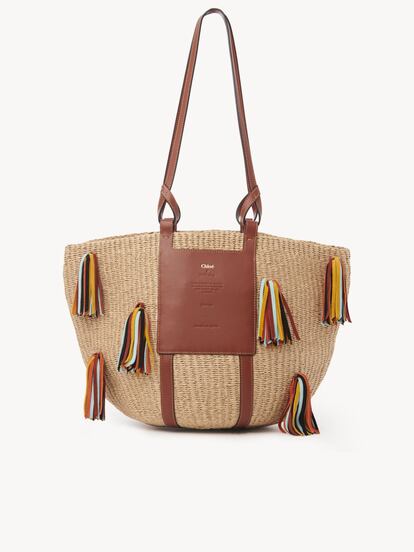 La cesta grande Chloé es un bolso de día espacioso con una actitud informal pero sofisticada. Anclada en el compromiso de la marca con la responsabilidad social, cuenta con un parche exterior que explica su historia: Ha sido realizado en colaboración con Mifuko, que en suajili significa bolsillo. Mediante una remuneración justa y una menor dependencia de la imprevisible agricultura como fuente de ingresos, la compañía empodera a sus artesanas de Kenia y se asegura de que nadie se quede con los bolsillos vacíos. Precio: 790 euros. www.chloe.com.