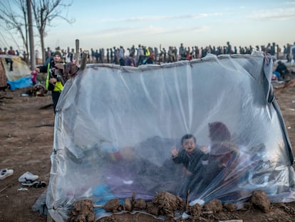 Una mujer siria y sus hijos esperan dentro de su tienda para recibir comida, este martes, en el paso fronterizo de Pazarkule, en Edirne.