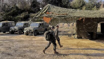 Dos dels soldats passant per davant dels vehicles i la carpa mimetitzada.