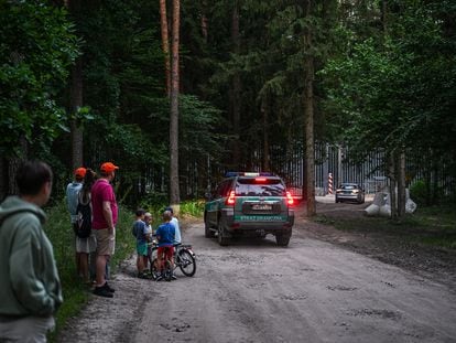 Un grupo de personas observa en la distancia la valla en la frontera entre Polonia y Bielorrusia, en Bialowieza, el pasado julio.