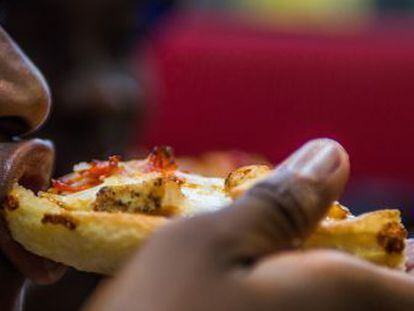 Un hombre come pizza en un restaurante.