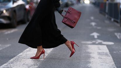 Una mujer pasea en París con unos zapatos de tacón rojos de Saint Laurent.