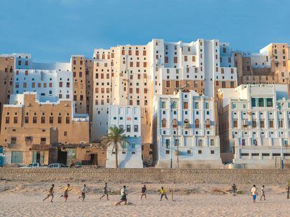 Jóvenes juegan en la arena ante varios edificios de la ciudad de Shibam, al oeste de la gobernación yemení de Hadramaut.
