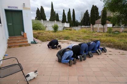 Varios hombres rezan antes del entierro de Tatary