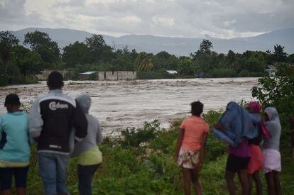 Diverses persones contemplen el riu inundat per l'huracà Matthew a Port-au-Prince (Haití).