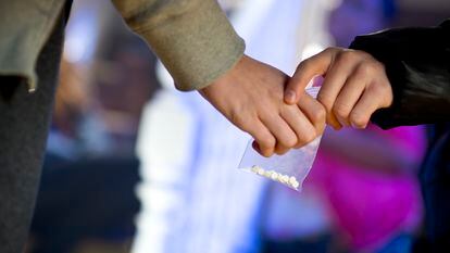 Una persona entrega a otra una bolsa con pastillas de MDMA.