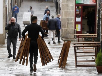 Un camarero trabaja en una terraza en una calle de Santiago de Compostela, donde se ha impuesto un máximo de cinco personas en las reuniones.