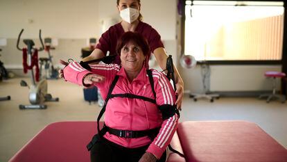 La rehabilitadora Amaia Aguas ayuda a poner el exoesqueleto a Milagros Azcona para realizar sus ejercicios.